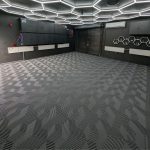 Modern dark-themed garage featuring Flexspec 3DFlex Pro grey interlocking floor tiles and a custom hexagon LED ceiling light grid.