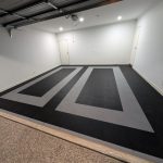 A clean white double garage with black vented floor tiles featuring two distinct grey rectangular parking bays.