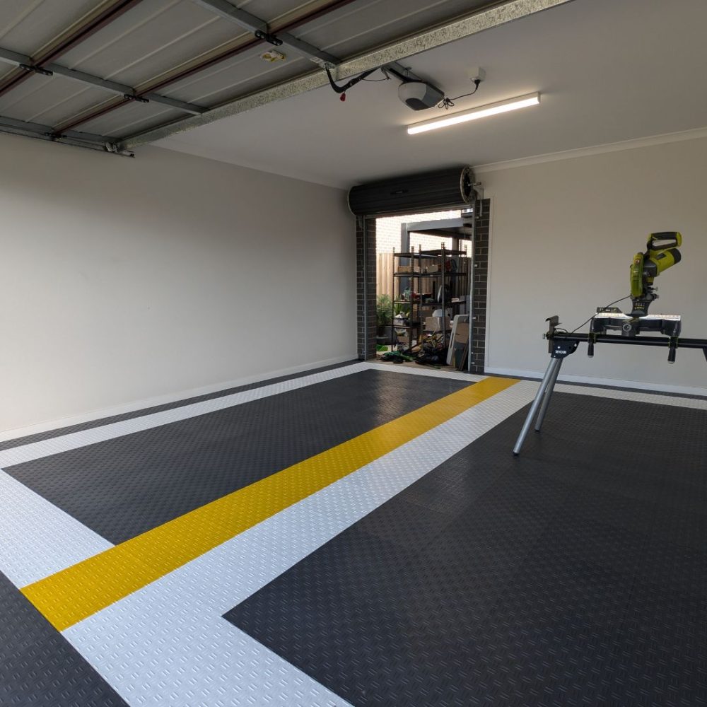 Heavy-duty DiamondFlex Pro garage workshop flooring featuring a custom yellow and white safety stripe to designate work zones.